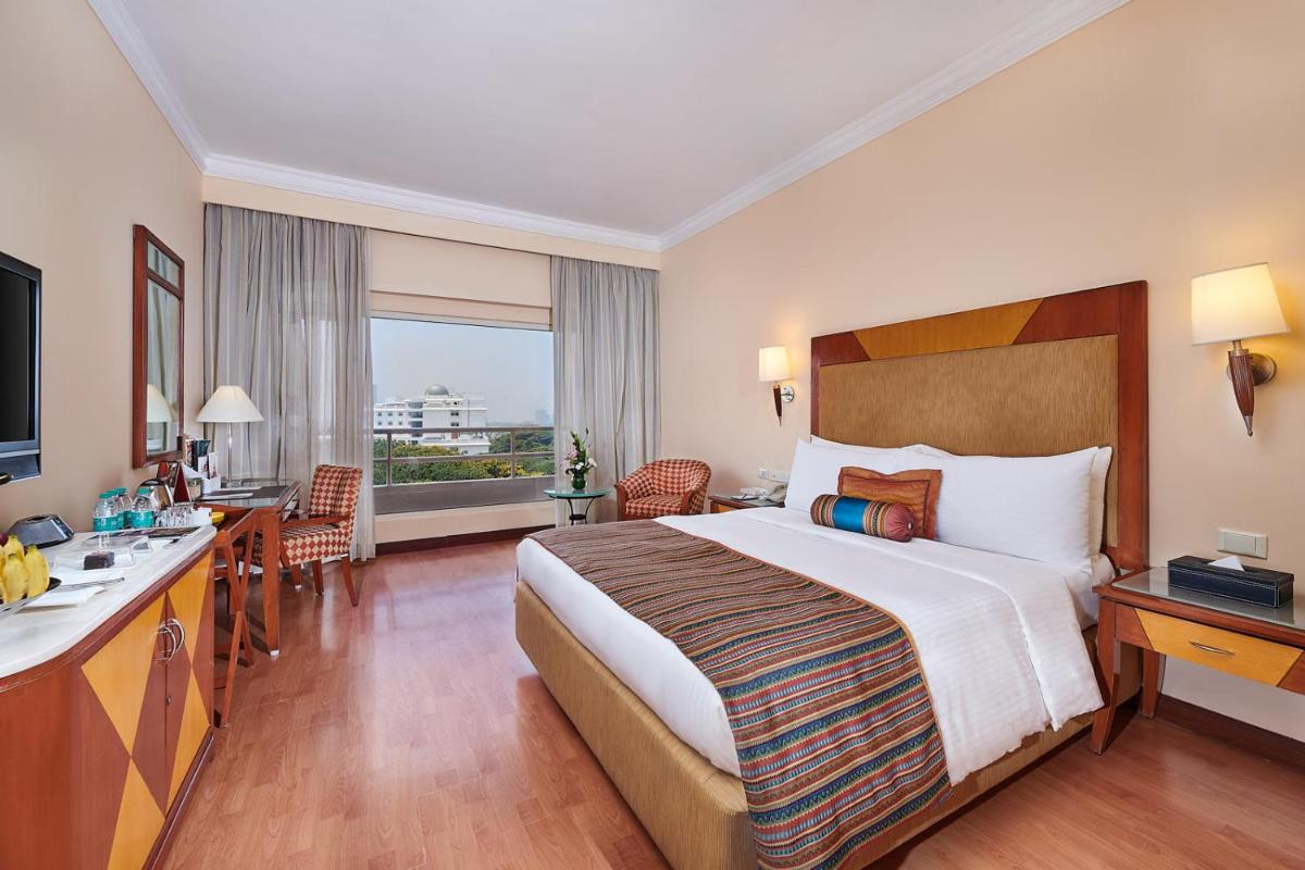 a hotel room with a large bed and a desk at The Lalit Ashok in Bengaluru a hotel room with a large bed and a desk at The Lalit Ashok in Bengaluru