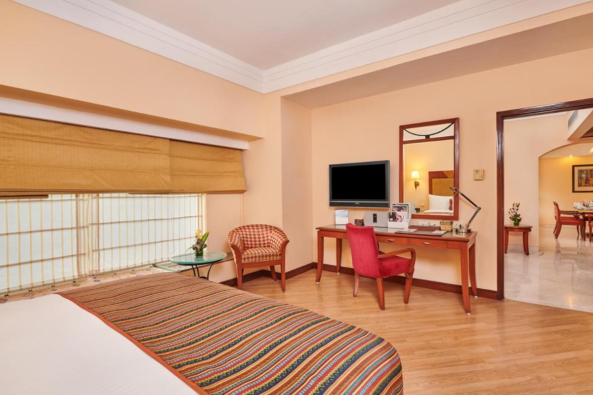 a hotel room with a bed and a desk and a television at The Lalit Ashok in Bengaluru a hotel room with a bed and a desk and a television at The Lalit Ashok in Bengaluru