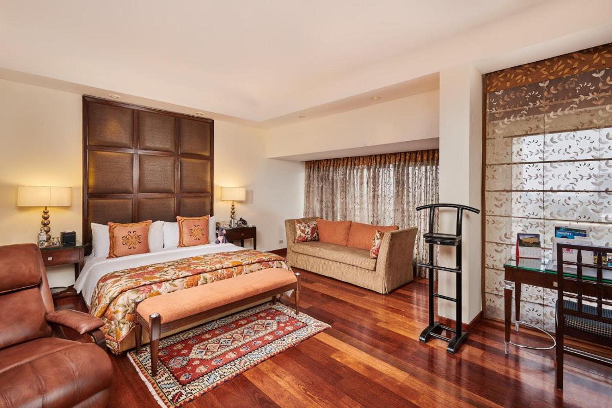 a bedroom with a large bed and a couch at The Lalit Ashok in Bengaluru a bedroom with a large bed and a couch at The Lalit Ashok in Bengaluru