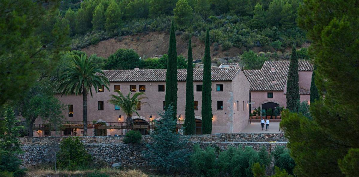 una casa grande con una persona caminando delante de ella en Terra Dominicata - Hotel & Winery - Adults Only, en Escaladei