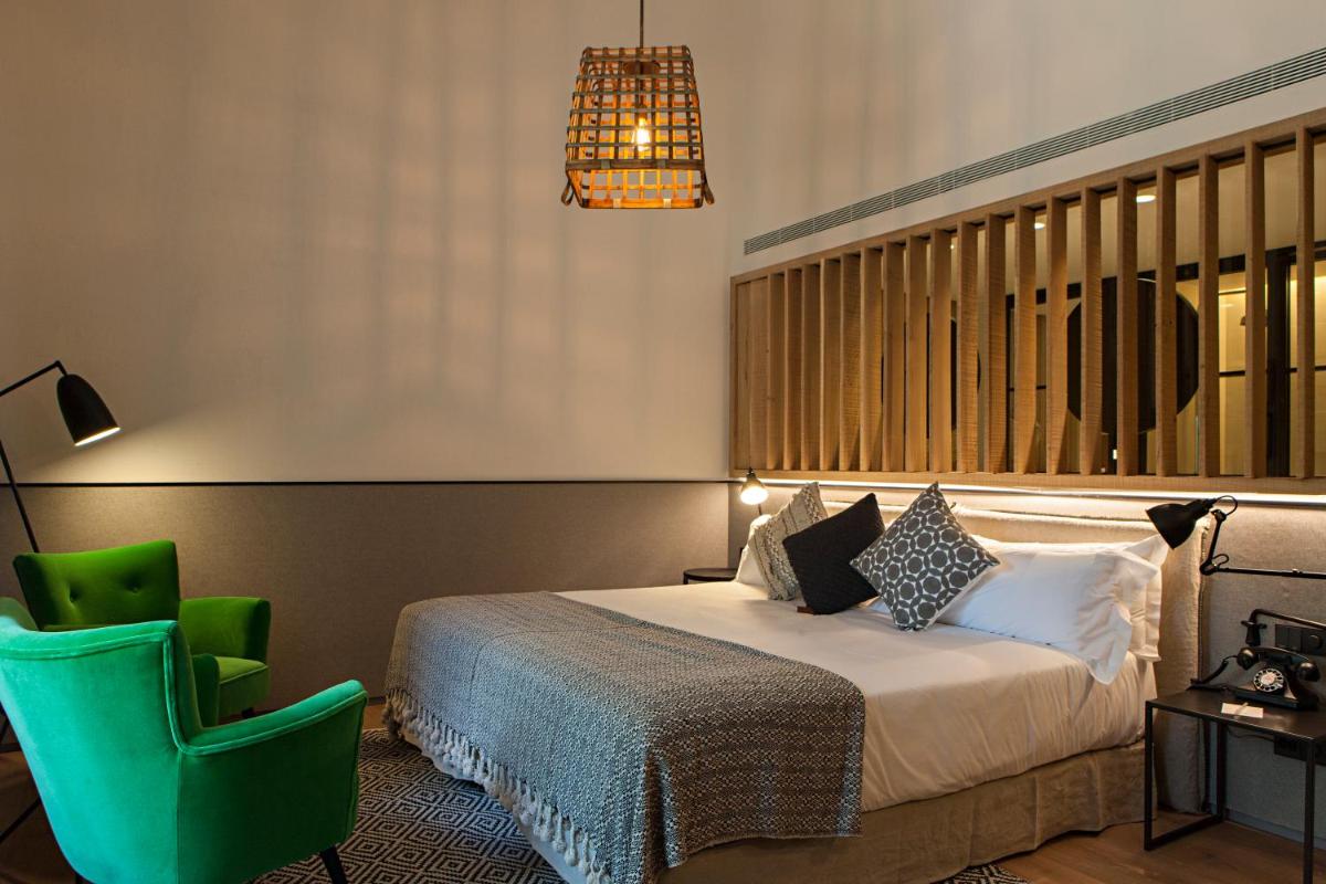 Un dormitorio con una cama y una silla verde. en Terra Dominicata - Hotel & Winery - Adults Only, en Escaladei