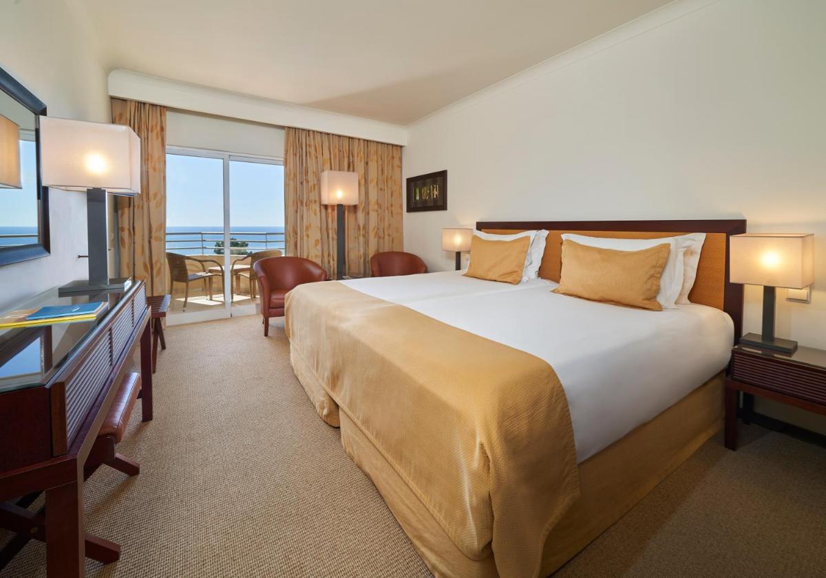 um quarto de hotel com uma cama grande e uma televisão em PortoBay Falesia em Albufeira mais 56 fotografias