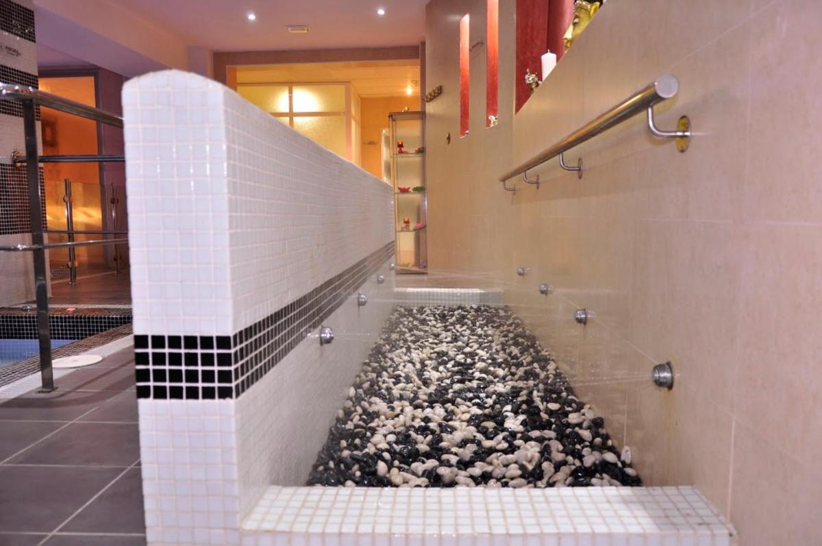 baño con ducha de piedra a ras de suelo con suelo de guijarros en Hotel & Spa PLAZA Arriate, en Arriate
