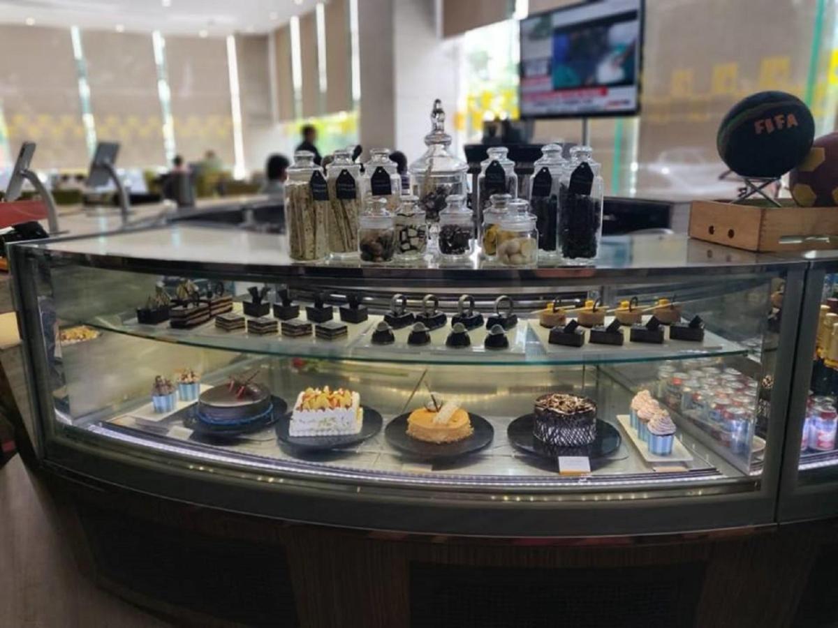 a display case filled with different types of desserts at Novotel Ahmedabad in Ahmedabad