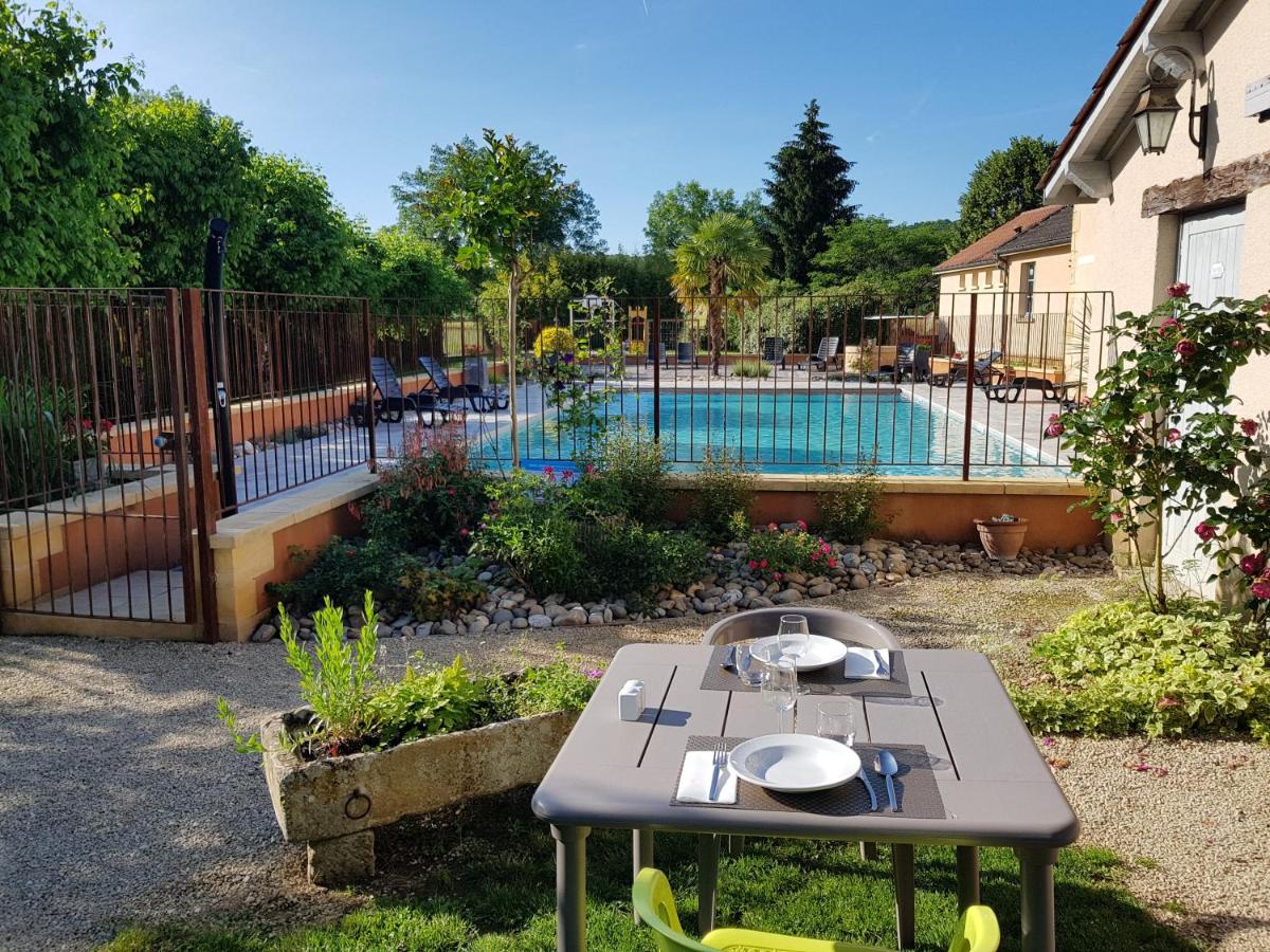 - une table dans une cour à côté d'une piscine dans l'établissement Logis Hotel Archambeau, à Thonac