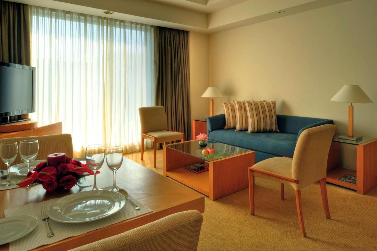 a living room with a blue couch and a table at Grand Hyatt Mumbai Hotel and Residences in Mumbai