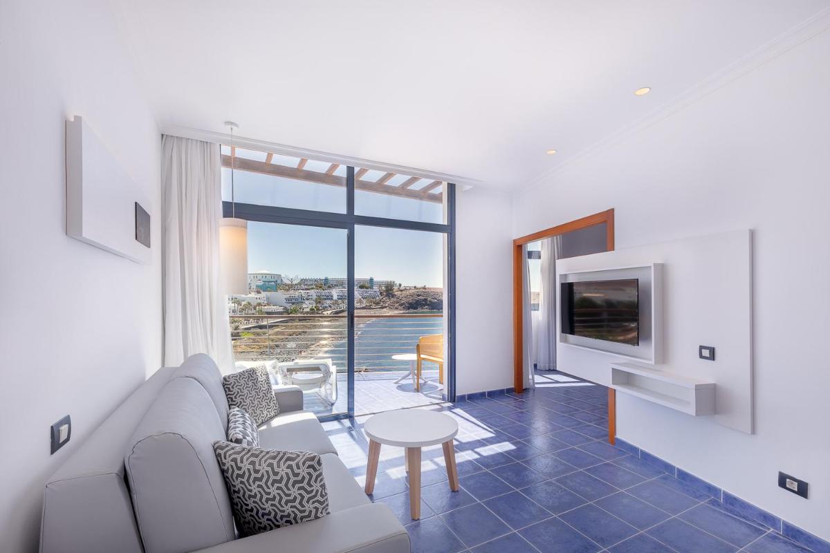 Una sala de estar con un sofá, un televisor y una mesa. en Hotel Mirador Papagayo by LIVVO, en Playa Blanca