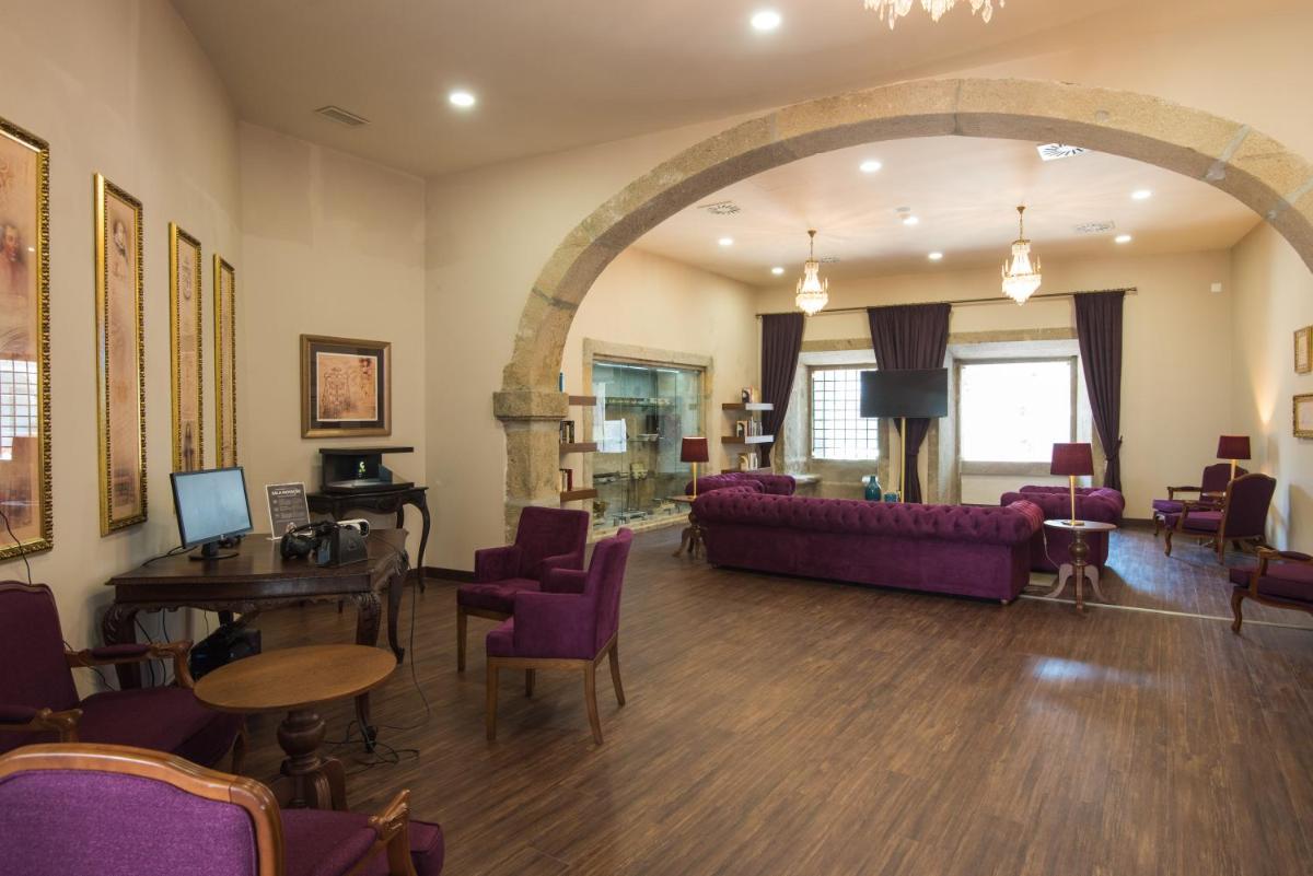 uma sala de estar com um sofá e cadeiras roxas em Vila Gale Collection Braga em Braga