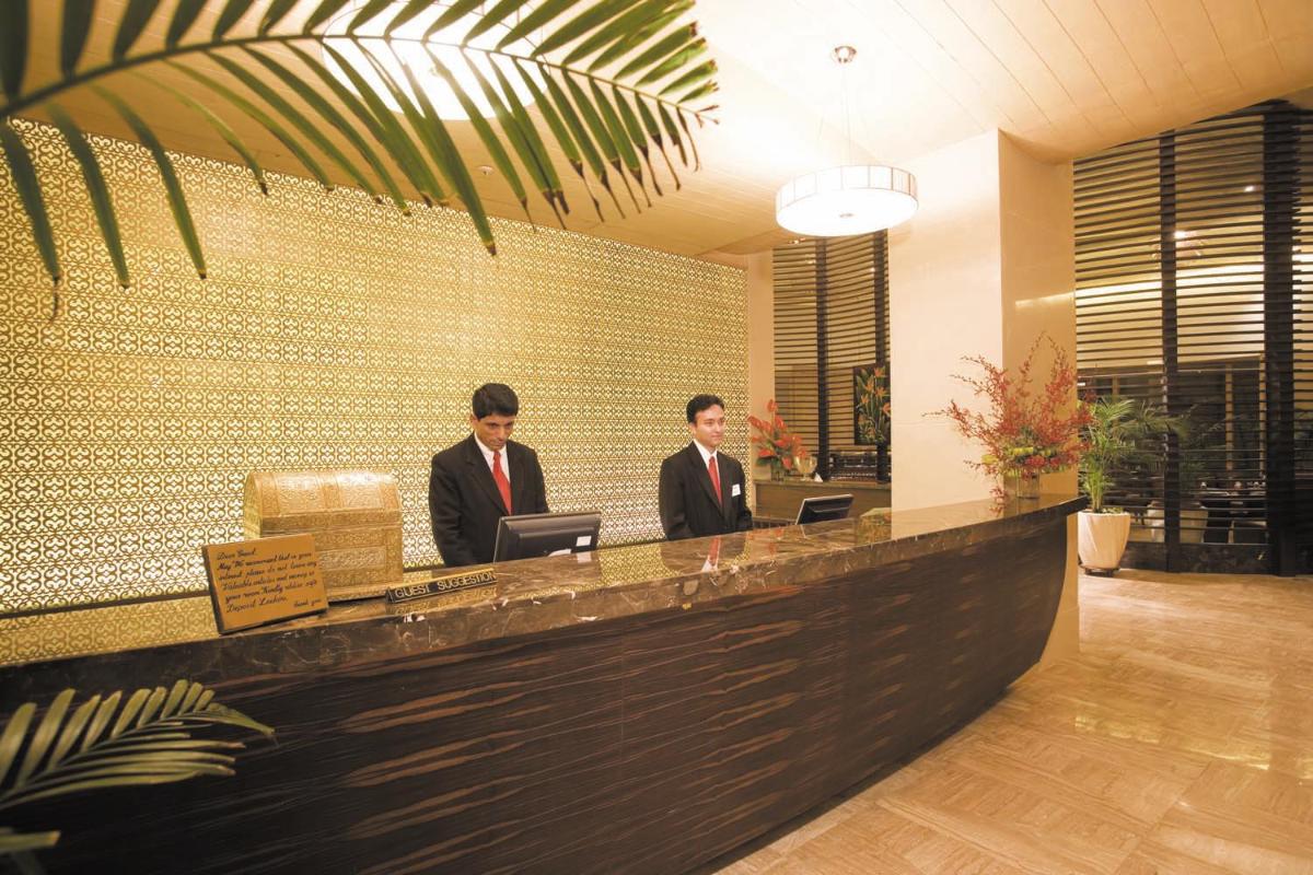 two men in suits sitting at a reception desk at The Retreat Hotel & Convention Centre in Mumbai
