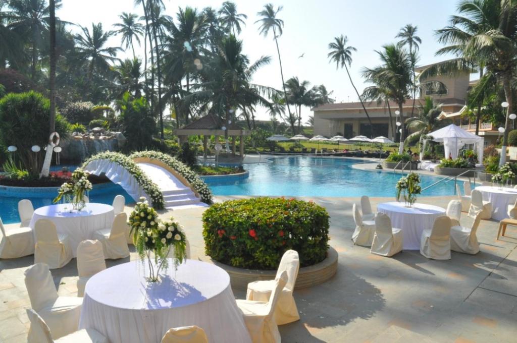 a pool with white tables and white chairs and a resort at The Retreat Hotel & Convention Centre in Mumbai