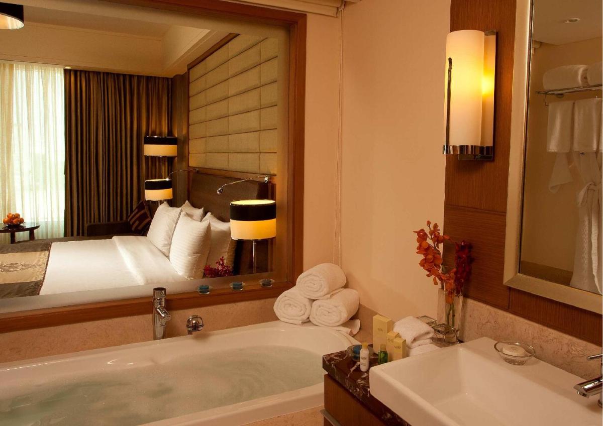 a bathroom with a bed and a tub and a mirror at Radisson Blu Hotel, Nagpur in Nagpur