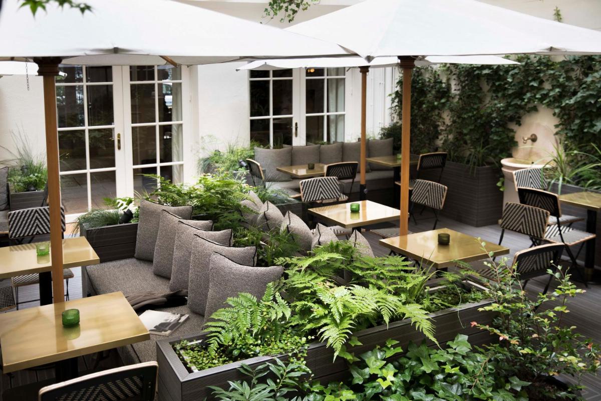 un patio extérieur avec tables, chaises et plantes dans l'établissement Hôtel D'Aubusson, à Paris 18 autres photos