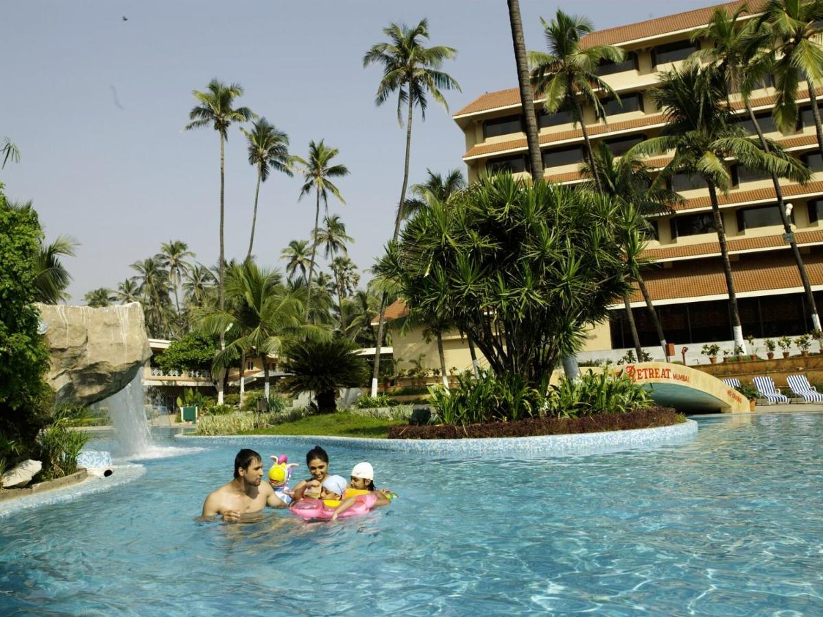 a man and two children in a swimming pool at a resort at The Retreat Hotel & Convention Centre in Mumbai