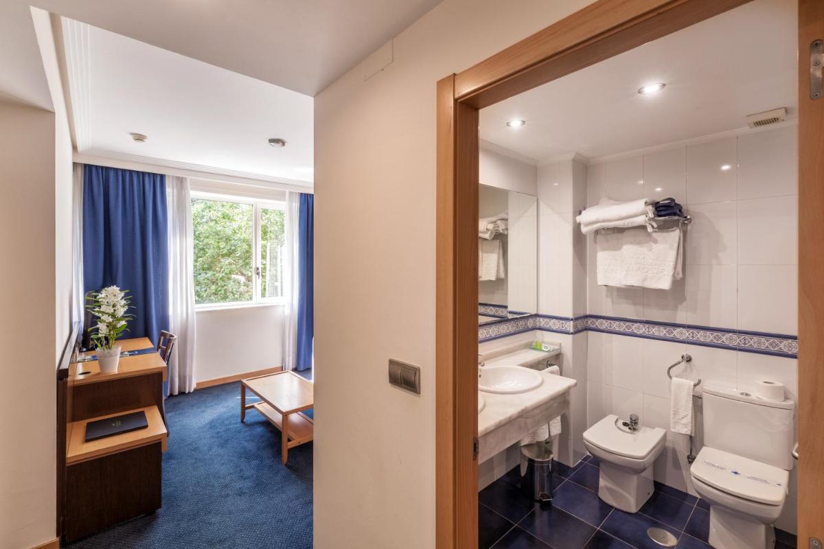 Un baño con lavabo, inodoro y espejo. en Hotel Balneario de Compostela, en Brión