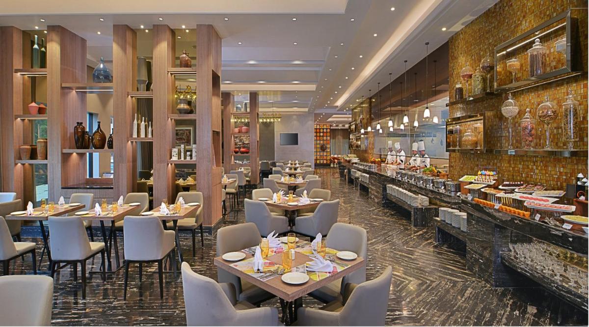 a restaurant with tables and chairs and a buffet at Radisson Mumbai Andheri MIDC in Mumbai a restaurant with tables and chairs and a buffet at Radisson Mumbai Andheri MIDC in Mumbai