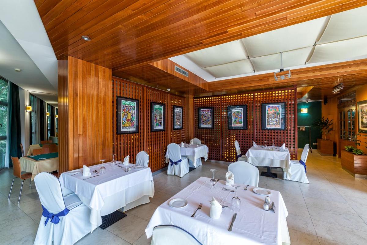 un restaurante con mesas y sillas blancas y paredes de madera en Hotel Balneario de Compostela, en Brión