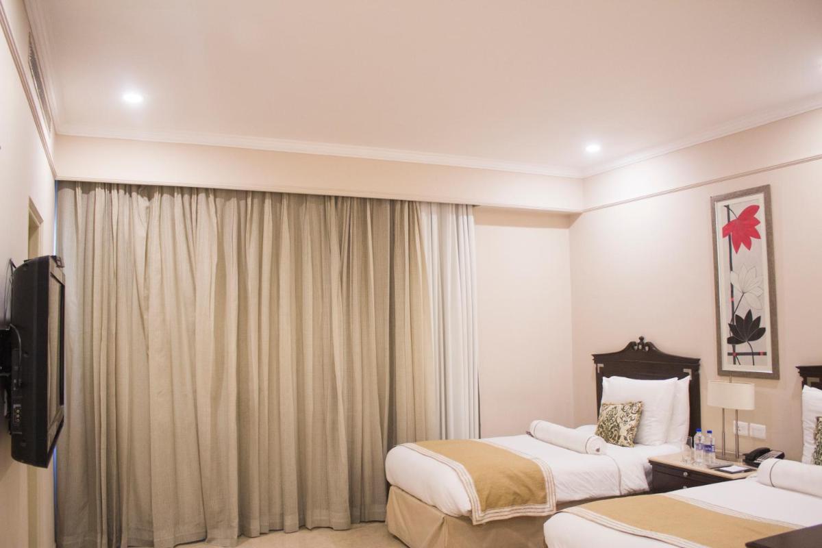 a hotel room with two beds and a television at The Claridges New Delhi in New Delhi a hotel room with two beds and a television at The Claridges New Delhi in New Delhi