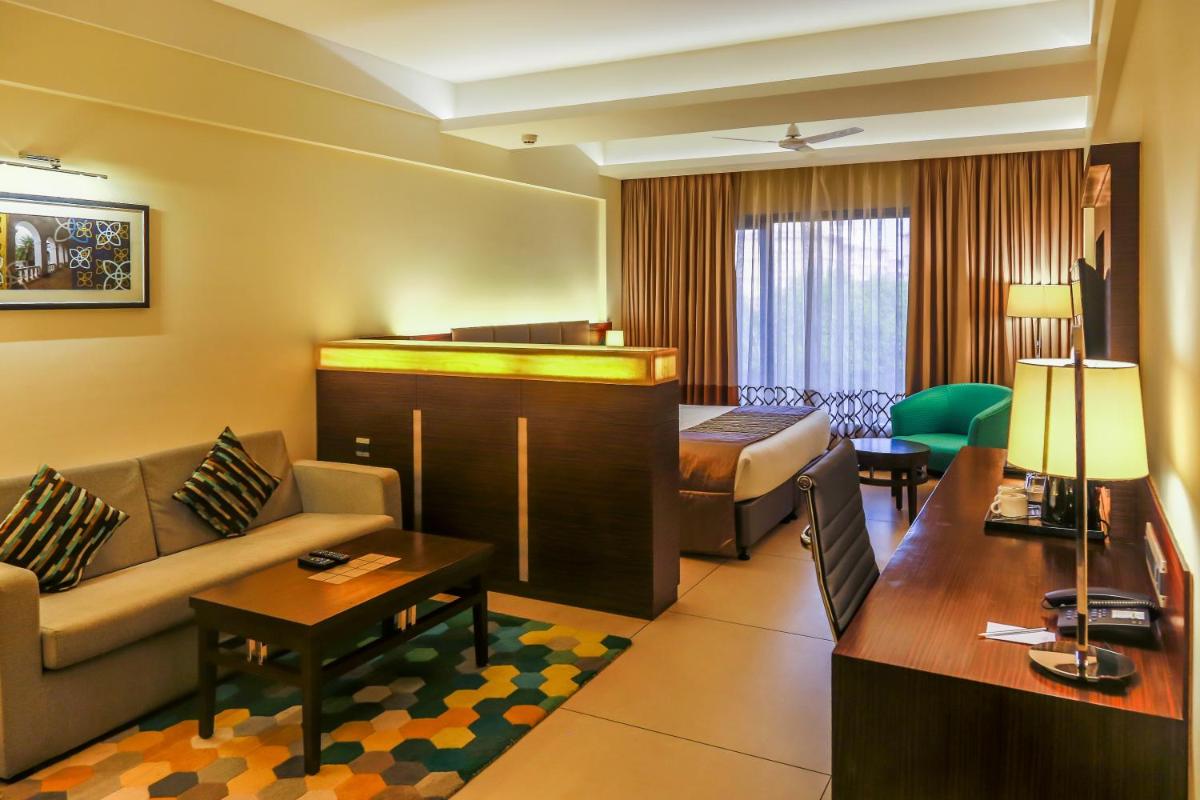 a hotel room with a couch and a bed at The Fern Kadamba Hotel And Spa in Old Goa