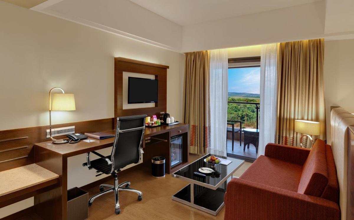 a hotel room with a desk and a chair at The Fern Kadamba Hotel And Spa in Old Goa