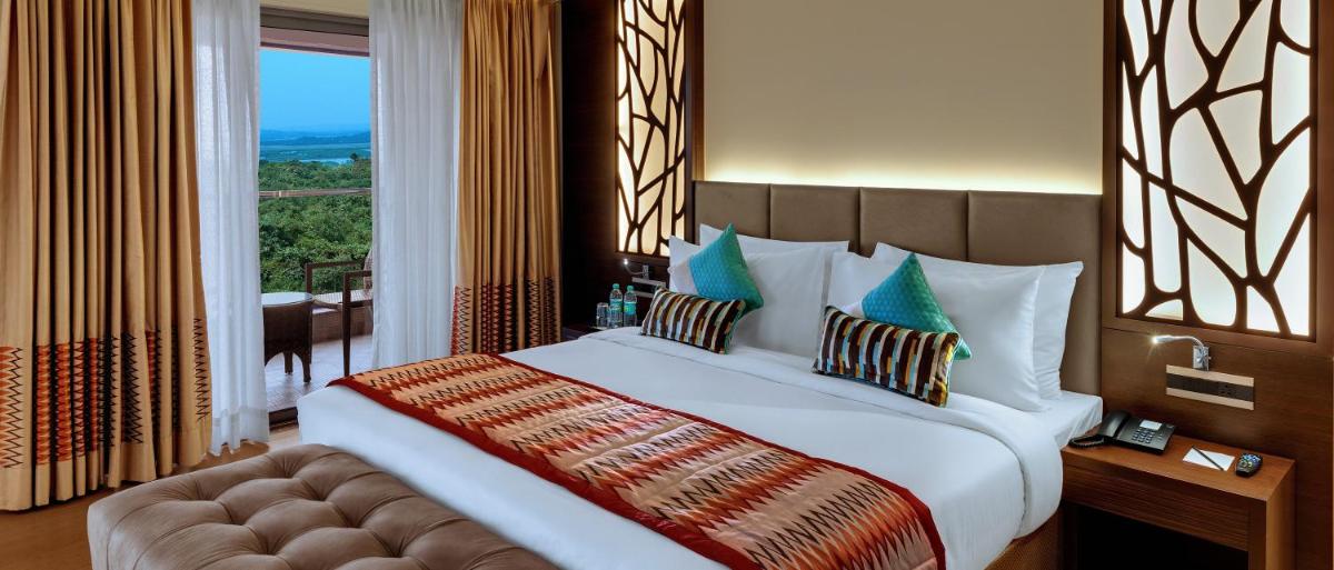 a bedroom with a large bed and a large window at The Fern Kadamba Hotel And Spa in Old Goa