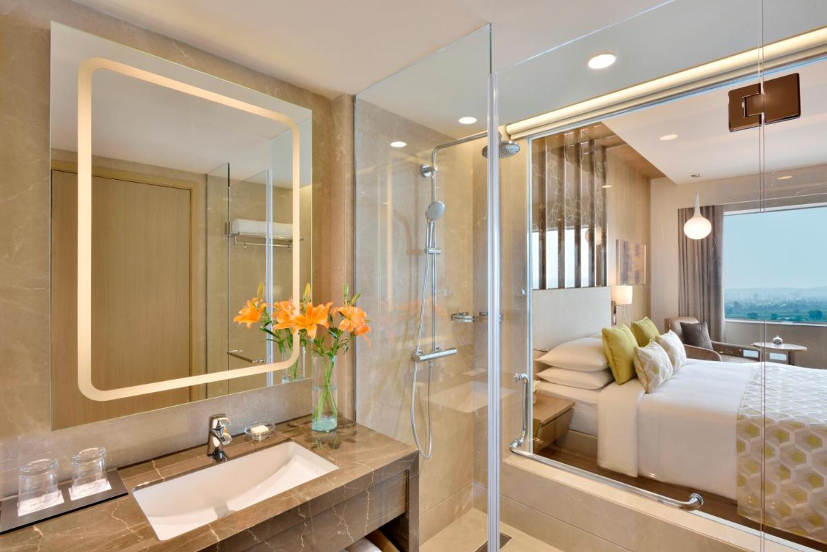 a bathroom with a bed and a sink and a mirror at Radisson Gurugram Udyog Vihar in Gurgaon a bathroom with a bed and a sink and a mirror at Radisson Gurugram Udyog Vihar in Gurgaon
