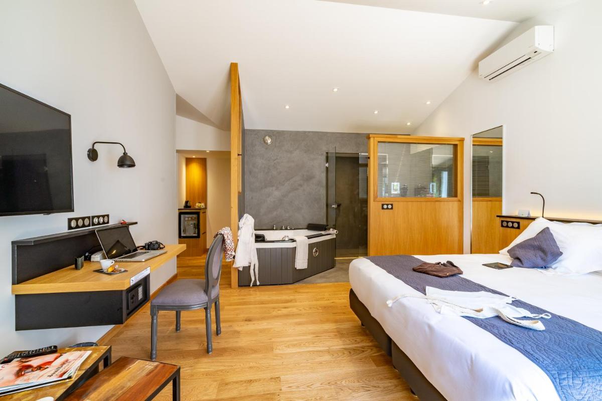 - une chambre avec un lit, un bureau et une baignoire dans l'établissement Hôtel Ile de Ré, au Bois-Plage-en-Ré