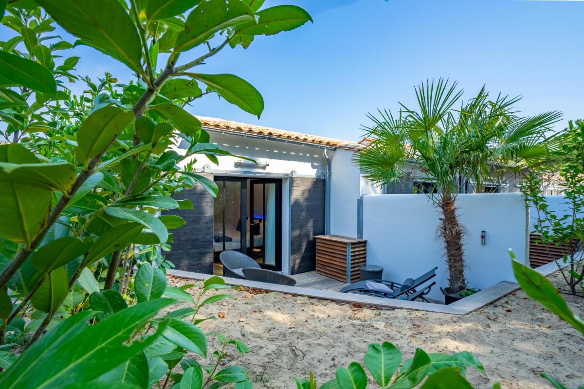 une maison sur la plage avec un palmier dans l'établissement Hôtel Ile de Ré, au Bois-Plage-en-Ré