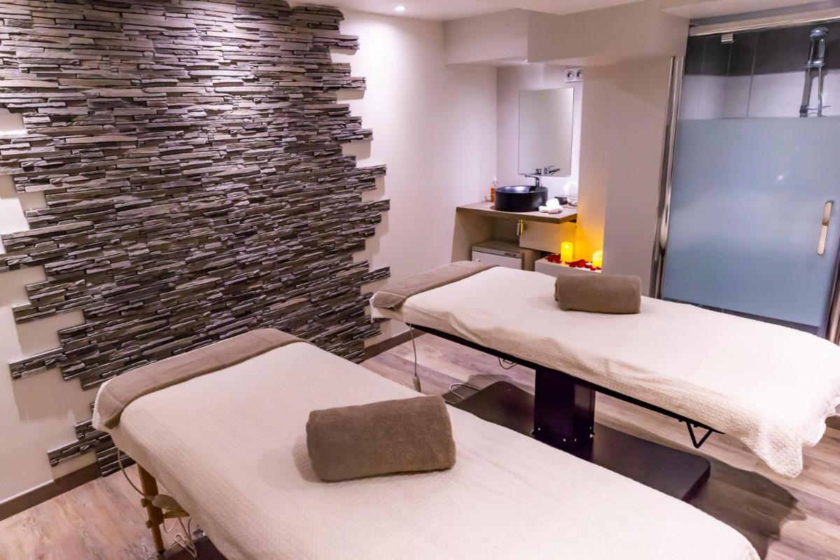 une salle de thérapie avec deux lits et un mur en pierre dans l'établissement Almoria Hôtel & SPA, à Deauville