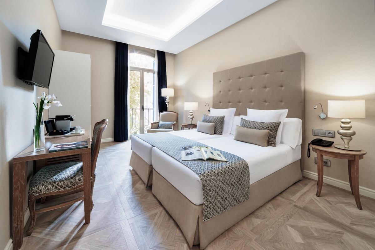 Un dormitorio con una cama, un escritorio y un televisor. en Lamaro Hotel, en Barcelona