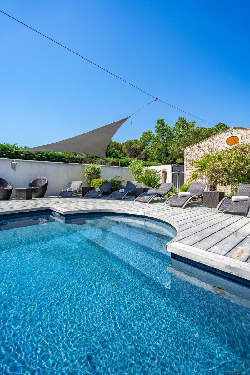 - une piscine avec des chaises à côté d'une maison dans l'établissement Elégance Suites Hôtel, au Bois-Plage-en-Ré