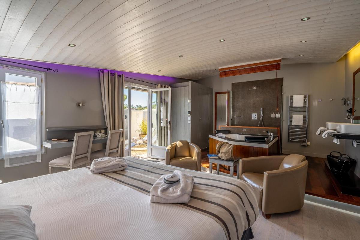une chambre avec un grand lit et un salon dans l'établissement Elégance Suites Hôtel, au Bois-Plage-en-Ré