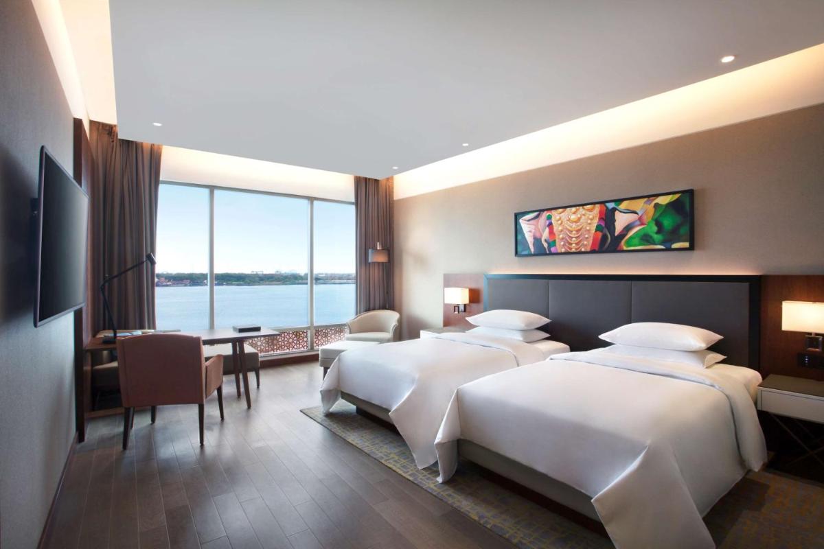 a hotel room with two beds and a desk and a room at Grand Hyatt Kochi Bolgatty in Cochin