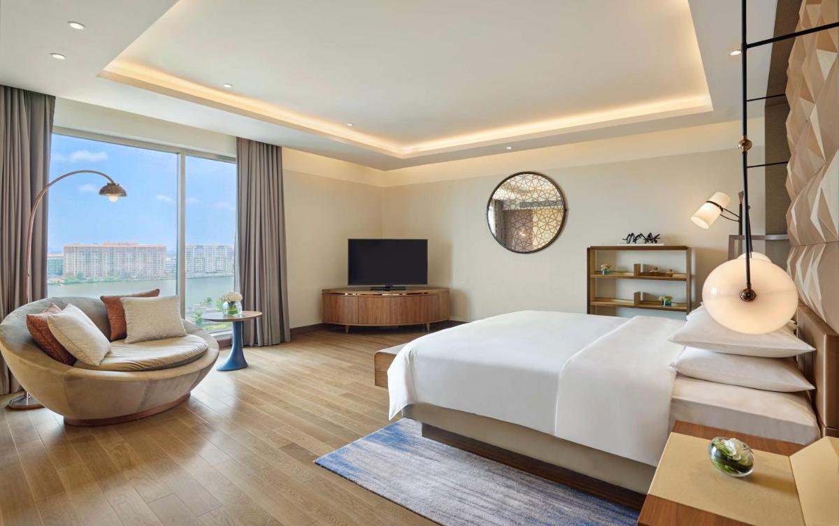 a bedroom with a bed and a chair and a television at Grand Hyatt Kochi Bolgatty in Cochin