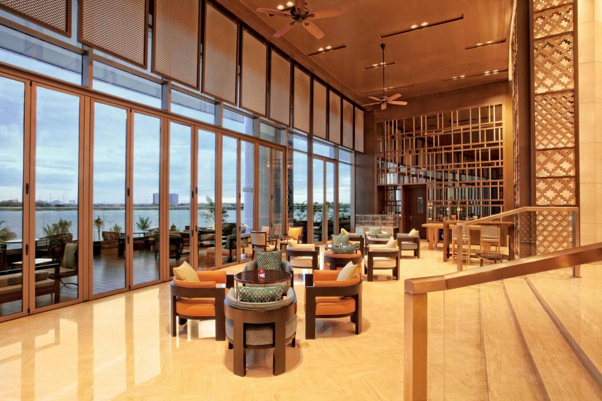 a lobby with tables and chairs and large windows at Grand Hyatt Kochi Bolgatty in Cochin