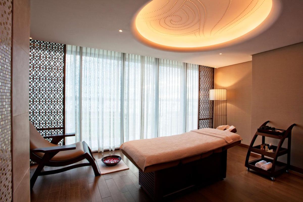 a bedroom with a bed and a chair in front of a window at Grand Hyatt Kochi Bolgatty in Cochin