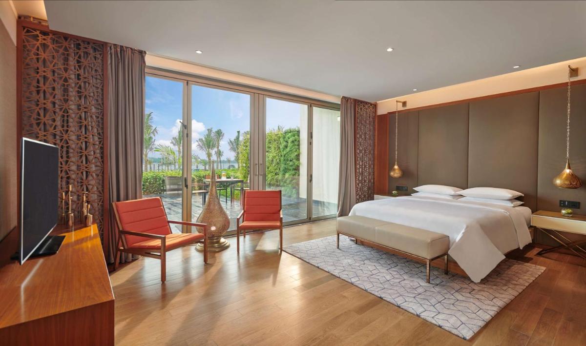 a bedroom with a bed and a television and a balcony at Grand Hyatt Kochi Bolgatty in Cochin