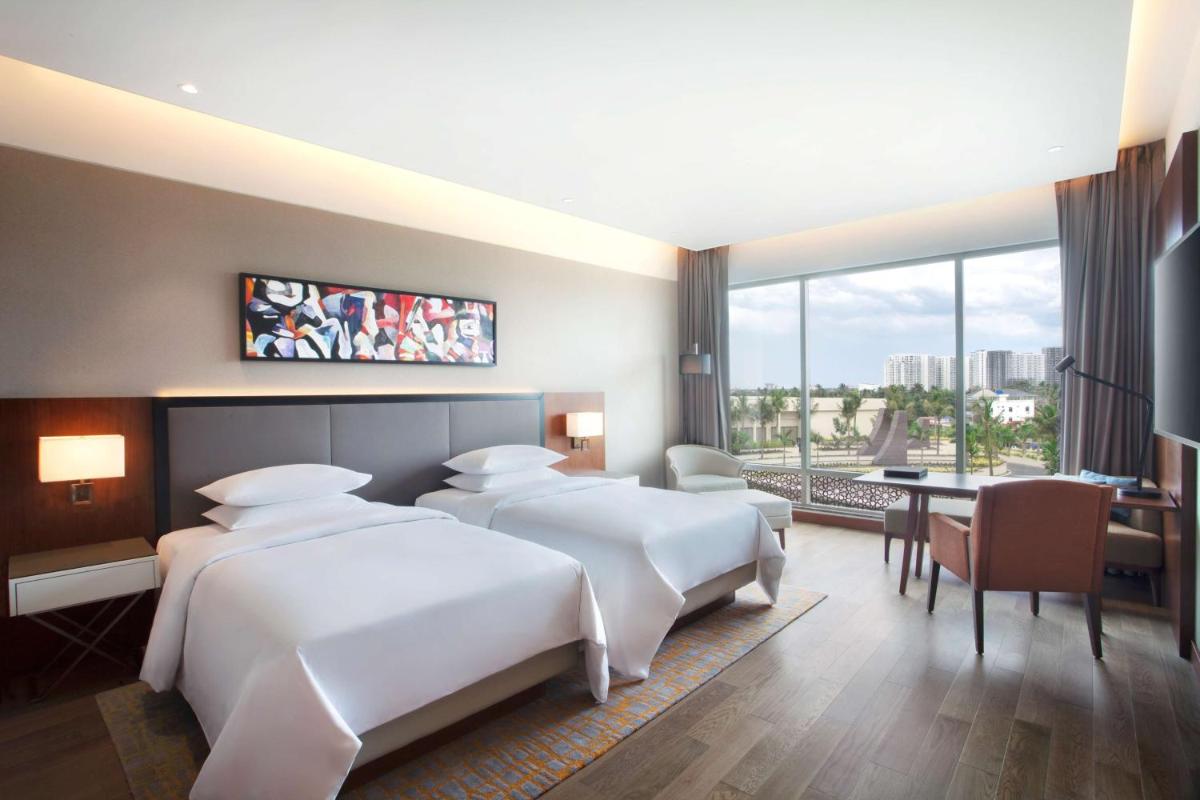 a hotel room with three beds and a table and a desk at Grand Hyatt Kochi Bolgatty in Cochin