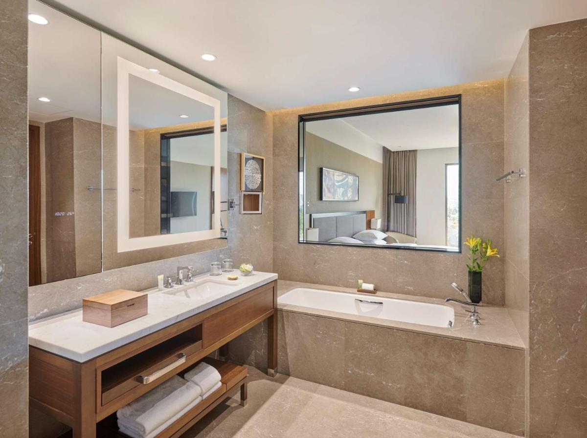 a bathroom with a sink and a tub and a mirror at Grand Hyatt Kochi Bolgatty in Cochin