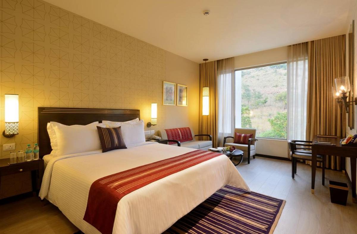 a hotel room with a bed and a large window at Marasa Sarovar Premiere in Tirupati