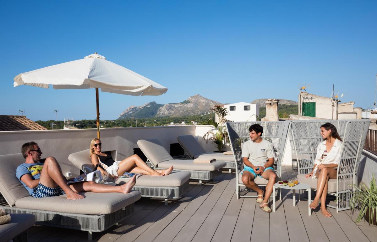 un grupo de personas sentadas en una terraza con un paraguas en Forum Boutique Hotel & Spa - Adults Only, en Alcudia