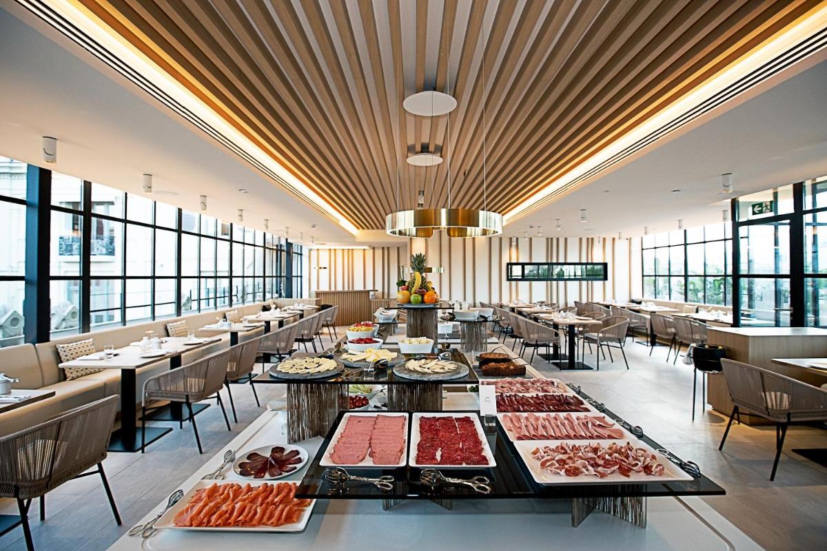 un gran comedor con mesas llenas de comida en Monument Hotel, en Barcelona