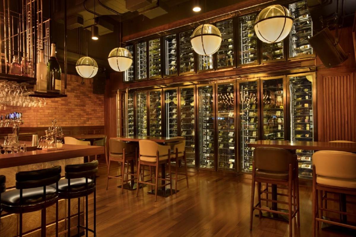 a bar with tables and chairs in a room with wine bottles at Taj Lands End in Mumbai a bar with tables and chairs in a room with wine bottles at Taj Lands End in Mumbai
