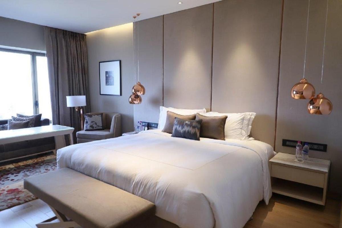 a bedroom with a large white bed and a living room at Taj Lands End in Mumbai a bedroom with a large white bed and a living room at Taj Lands End in Mumbai