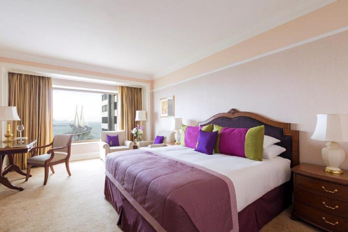a bedroom with a large bed with purple and yellow pillows at Taj Lands End in Mumbai a bedroom with a large bed with purple and yellow pillows at Taj Lands End in Mumbai