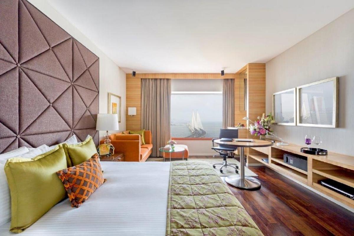 a hotel room with a bed and a desk and a room at Taj Lands End in Mumbai a hotel room with a bed and a desk and a room at Taj Lands End in Mumbai