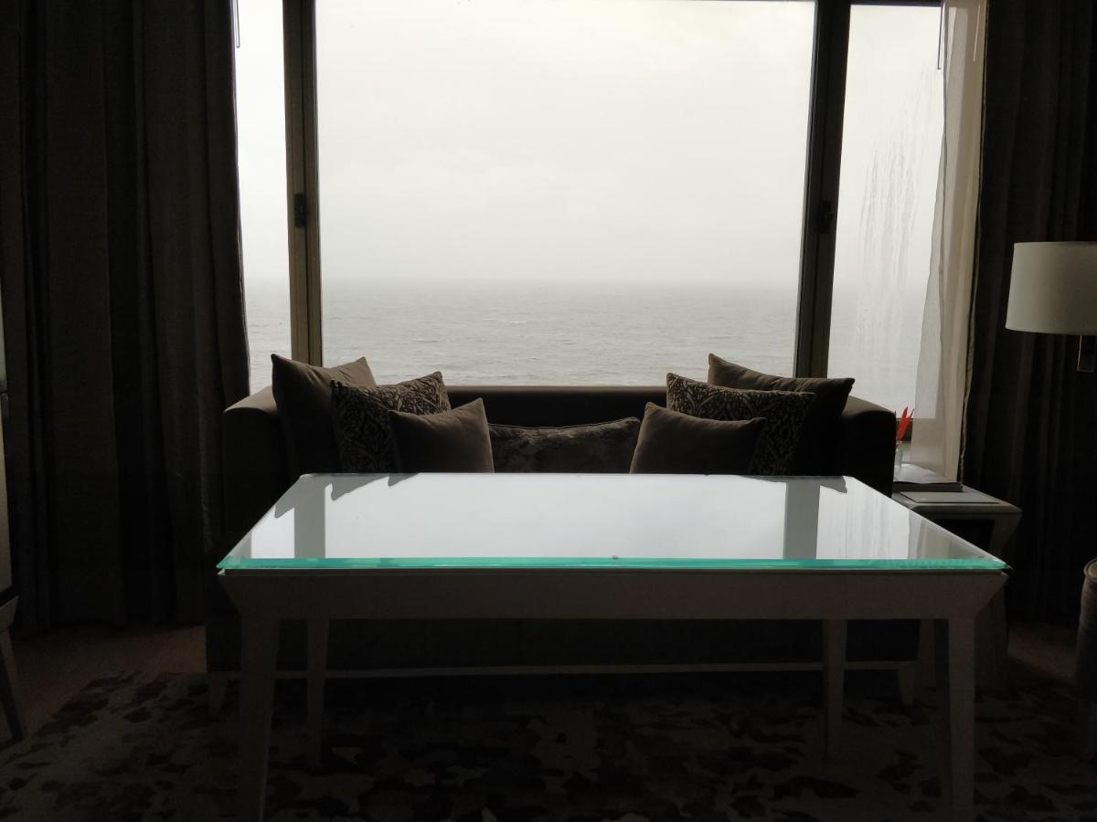a living room with a couch and a large window at Taj Lands End in Mumbai a living room with a couch and a large window at Taj Lands End in Mumbai