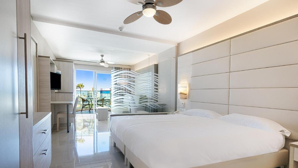 Un dormitorio blanco con una cama y un ventilador de techo. en Bull Dorado Beach & SPA, en La Playa de Arguineguín