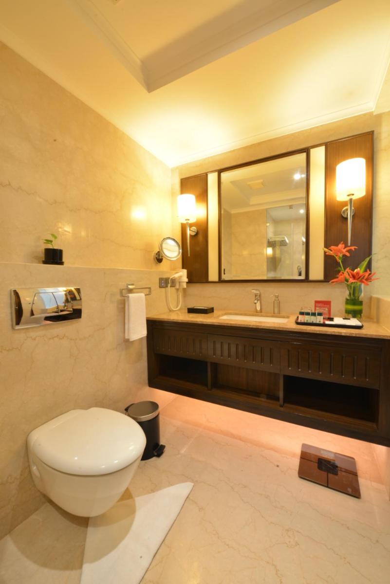 a bathroom with a toilet and a sink at Ramada Plaza Chennai in Chennai