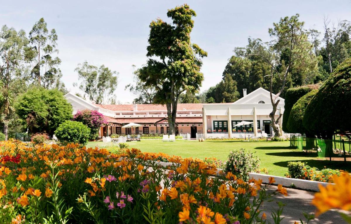 a garden with flowers in front of a building at Savoy - IHCL SeleQtions in Ooty