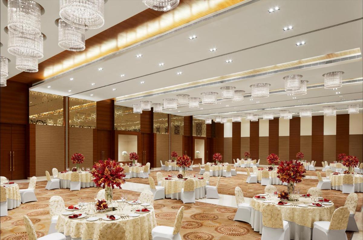 a banquet hall with white tables and chairs and chandeliers at Taj Swarna, Amritsar in Amritsar